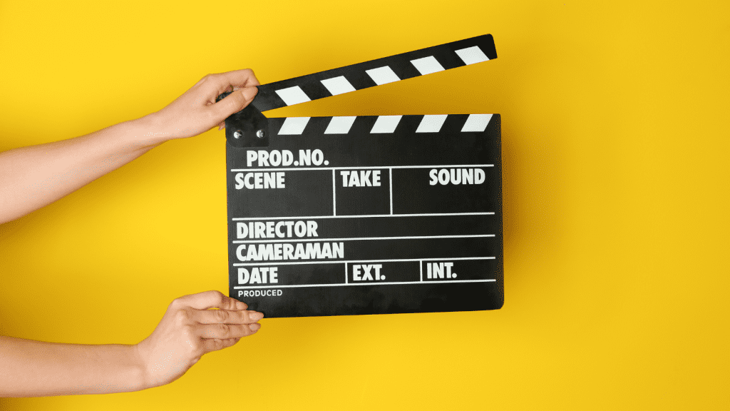 Picture of someone holding a movie action symbol with a yellow background